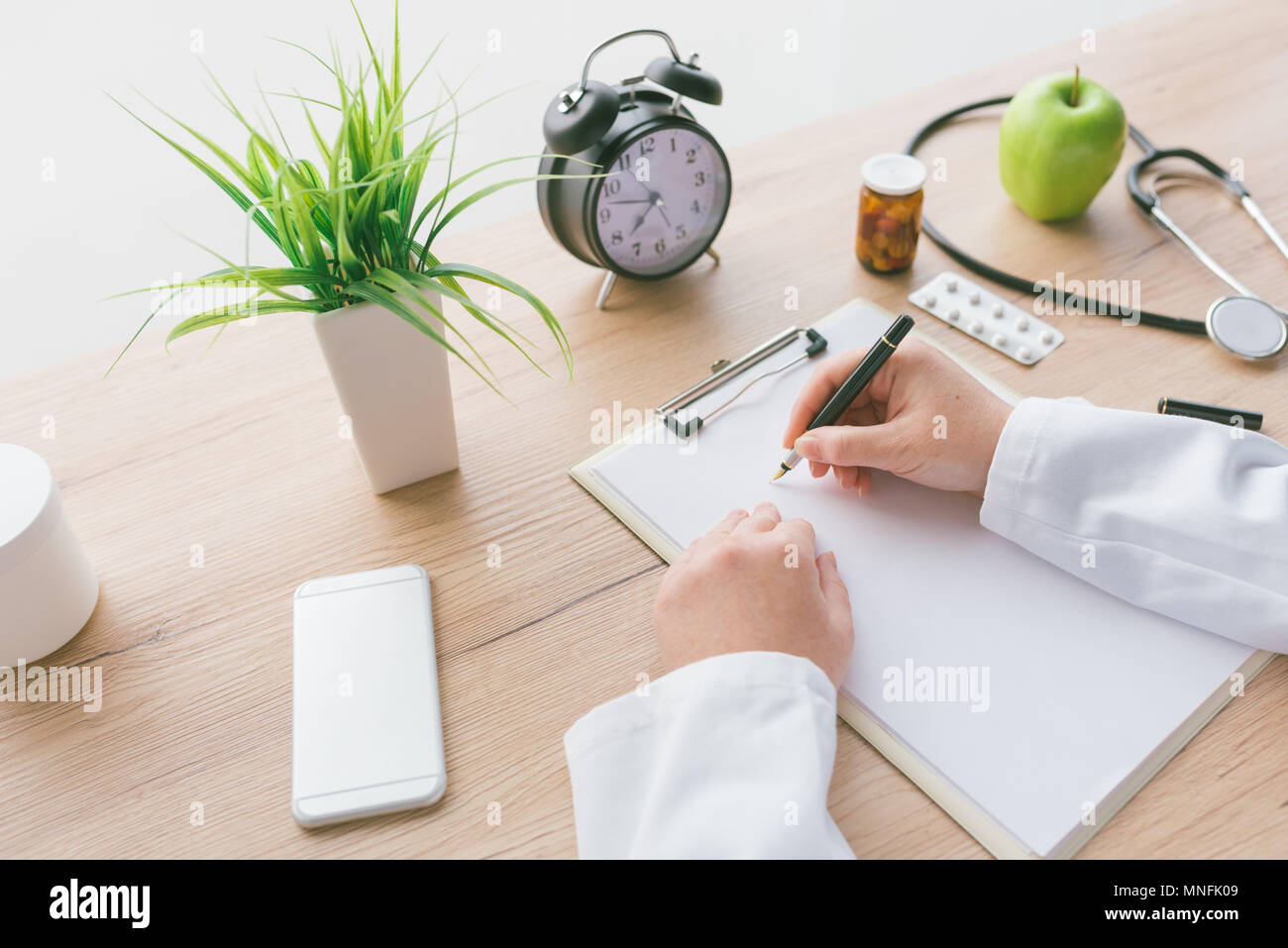 Femme médecin à écrire des notes, les antécédents médicaux du patient ou la médecine prescription sur presse-papiers papier pendant l'examen médical à l'hôpital office Banque D'Images