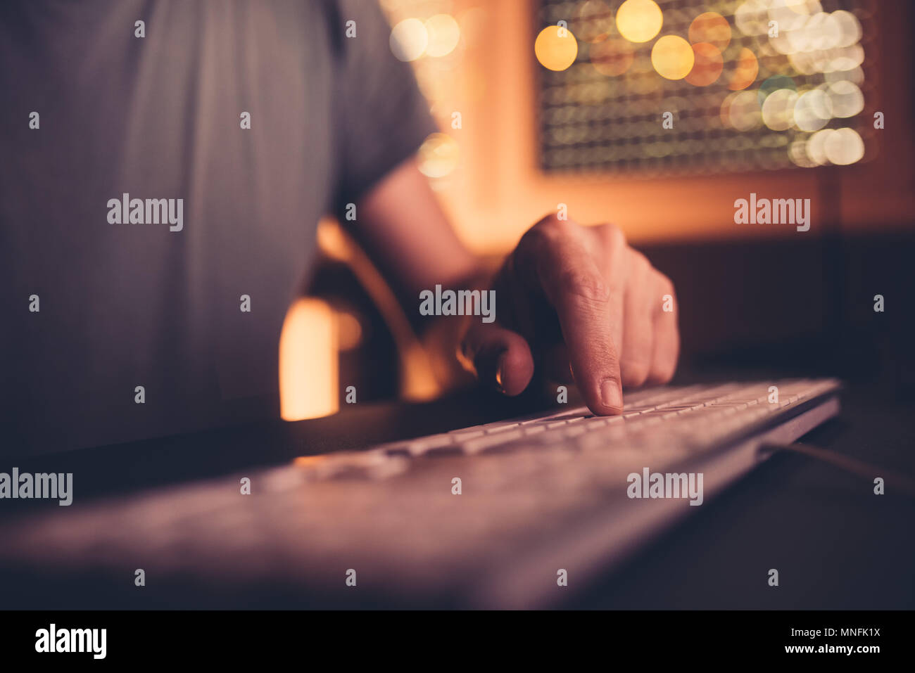 Doigt sur le clavier de l'ordinateur. Touches de l'ordinateur de l'homme entrant dans le bureau d'accueil de l'intérieur d'éclairage faible, selective focus Banque D'Images