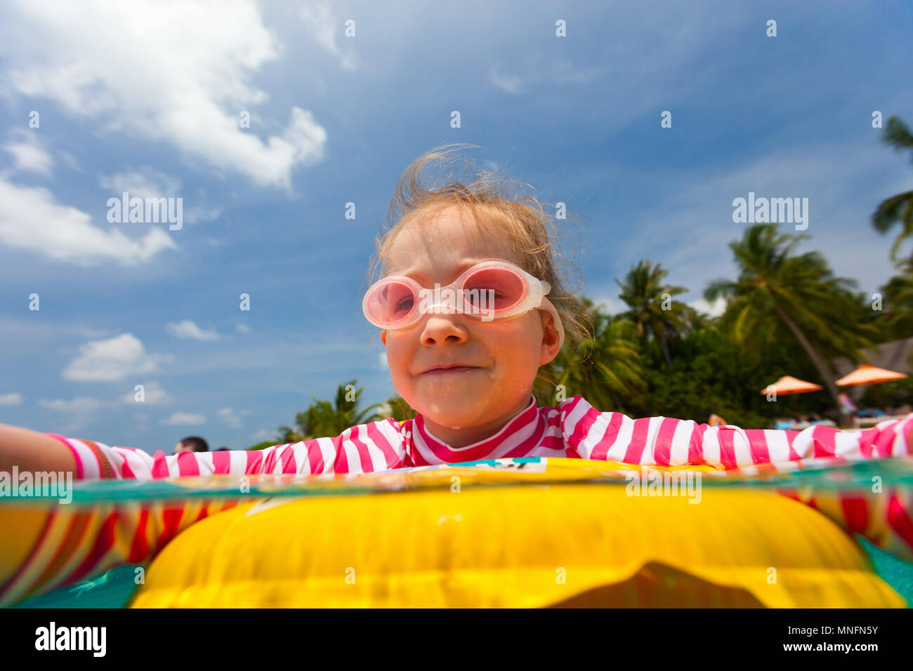 Adorable petite fille avec anneau gonflable jaune de nager dans une piscine en vacances Banque D'Images