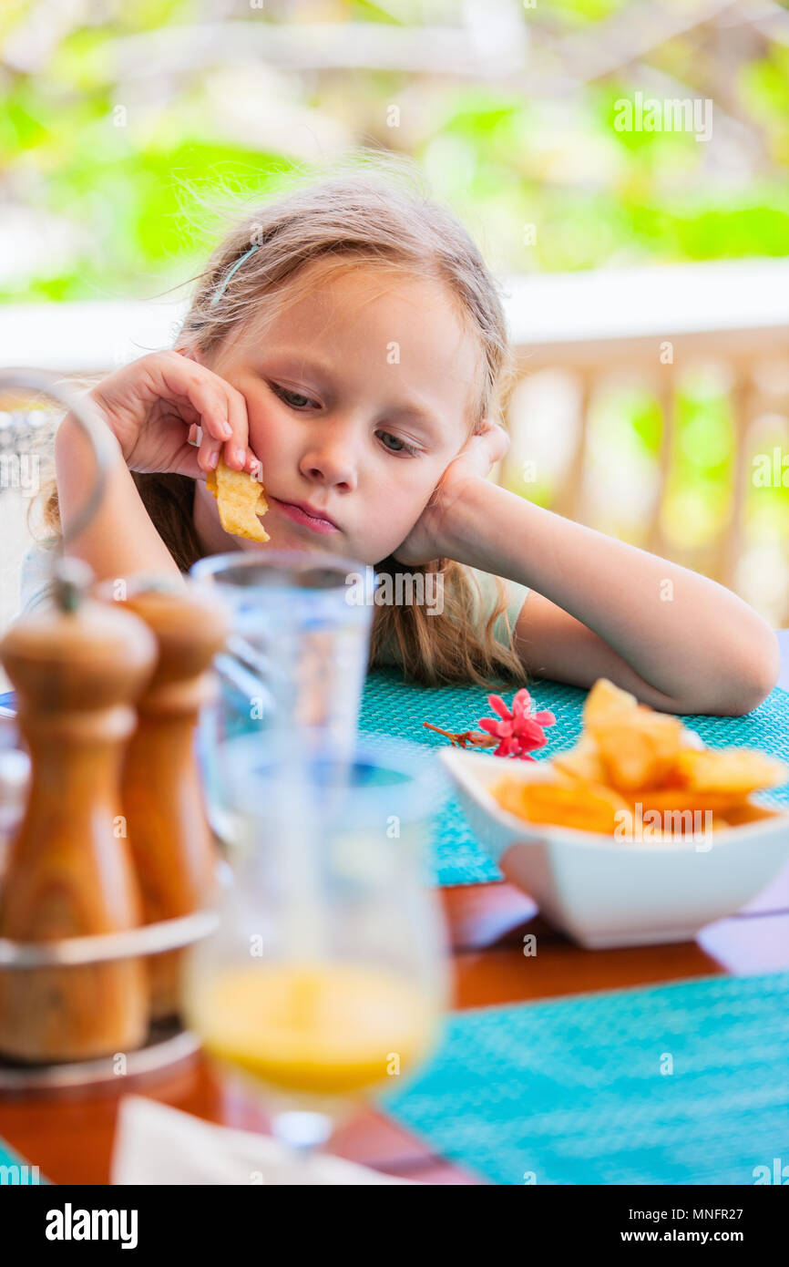 Adorable petite fille eating potato chips au déjeuner restaurant Banque D'Images