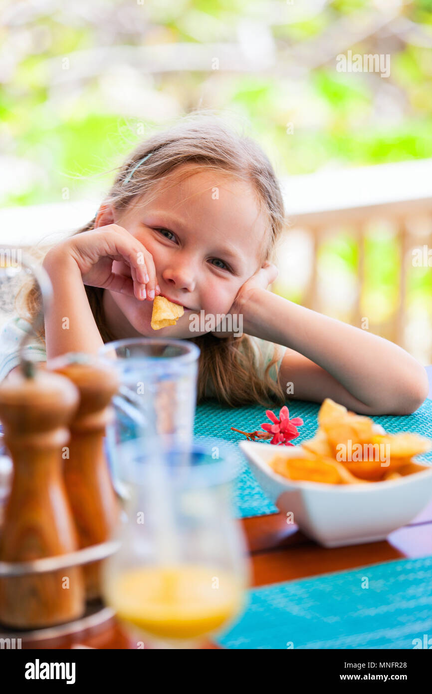 Adorable petite fille profiter de manger des croustilles au restaurant Banque D'Images