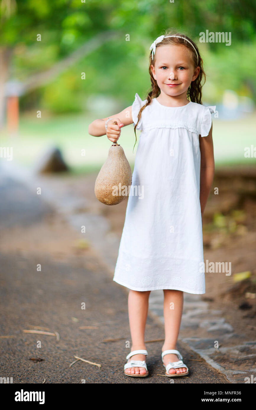 Charmante petite fille à l'extérieur tenant un fruit tropical Banque D'Images