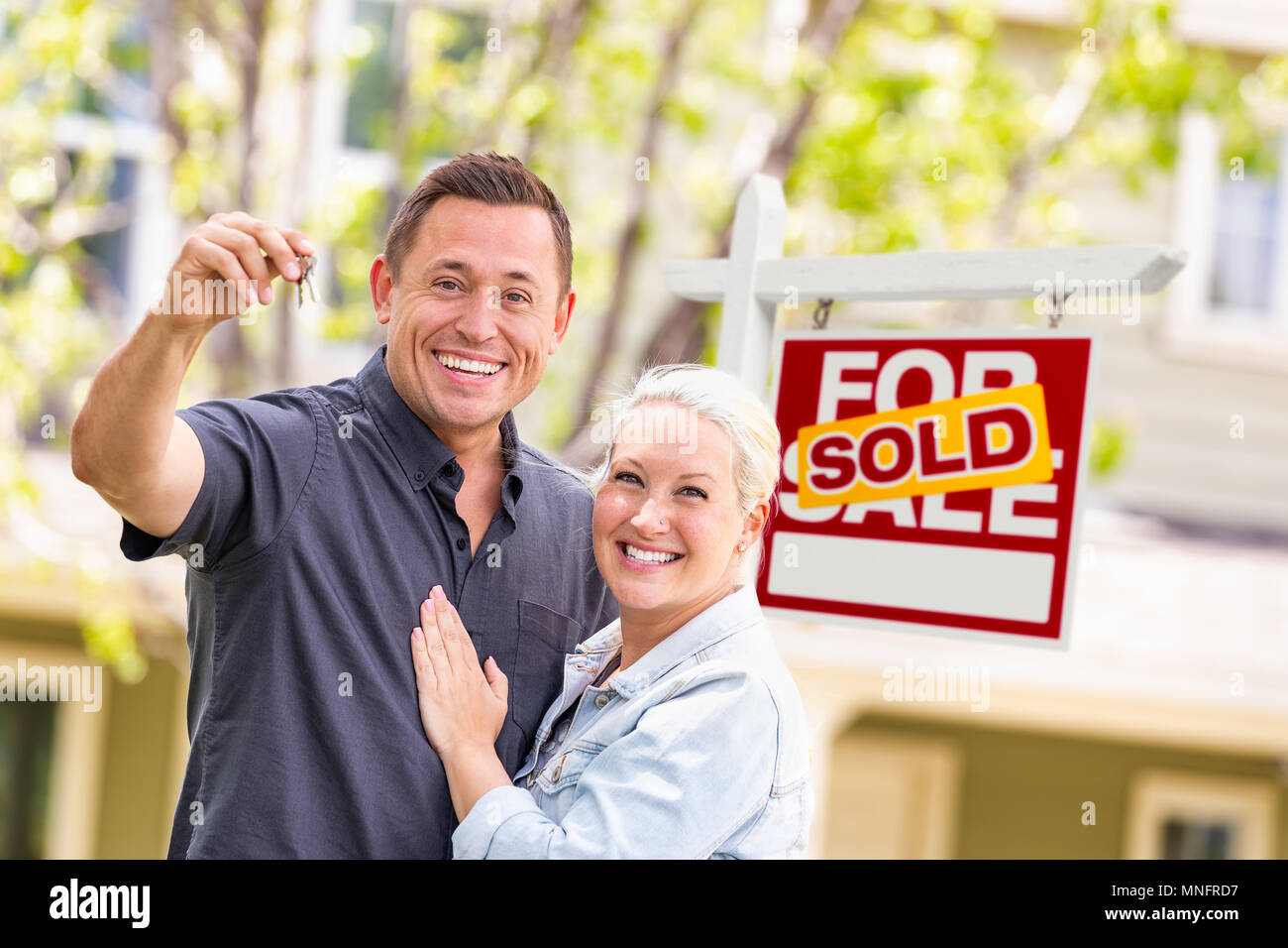 Caucasian Couple in front of vendu enseigne immobilière et de la Chambre avec des clés Banque D'Images
