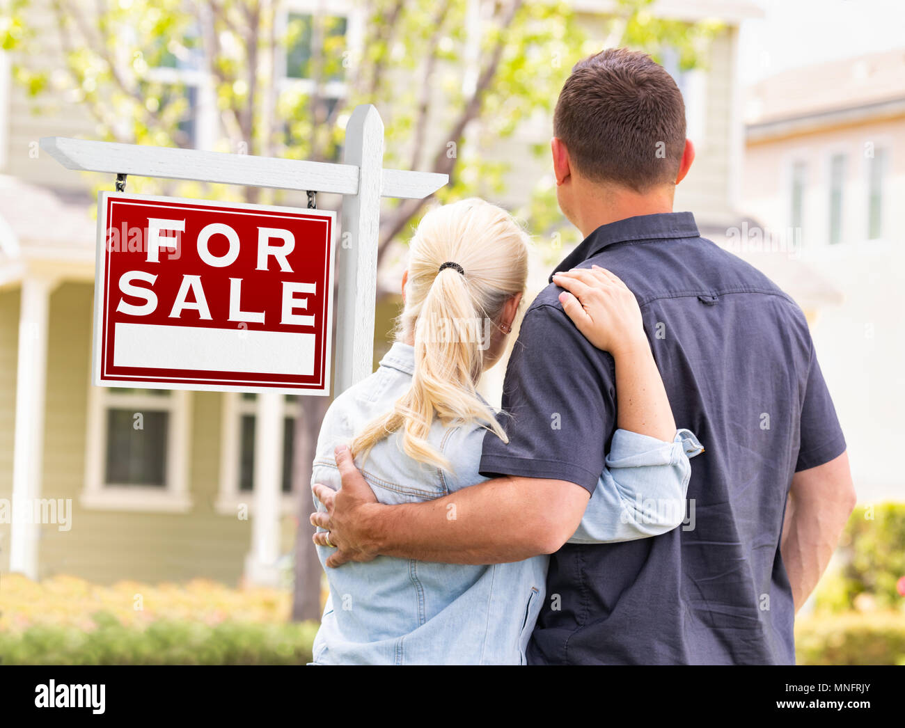 Couple face à l'avant du vendu enseigne immobilière et de la Chambre. Banque D'Images