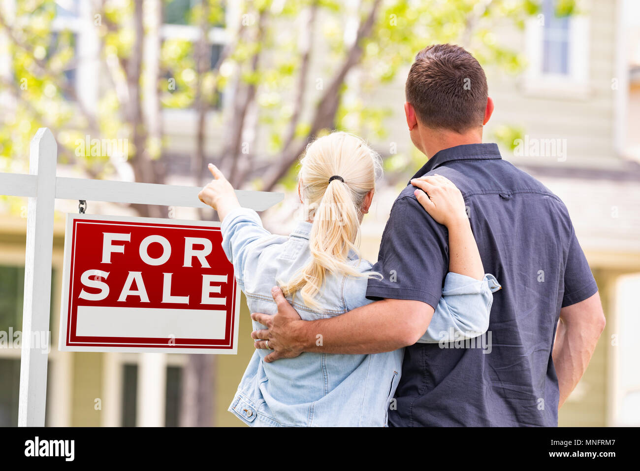 Caucasian Couple confrontés et pointant vers l'avant de Achat Immobilier signe et maison. Banque D'Images