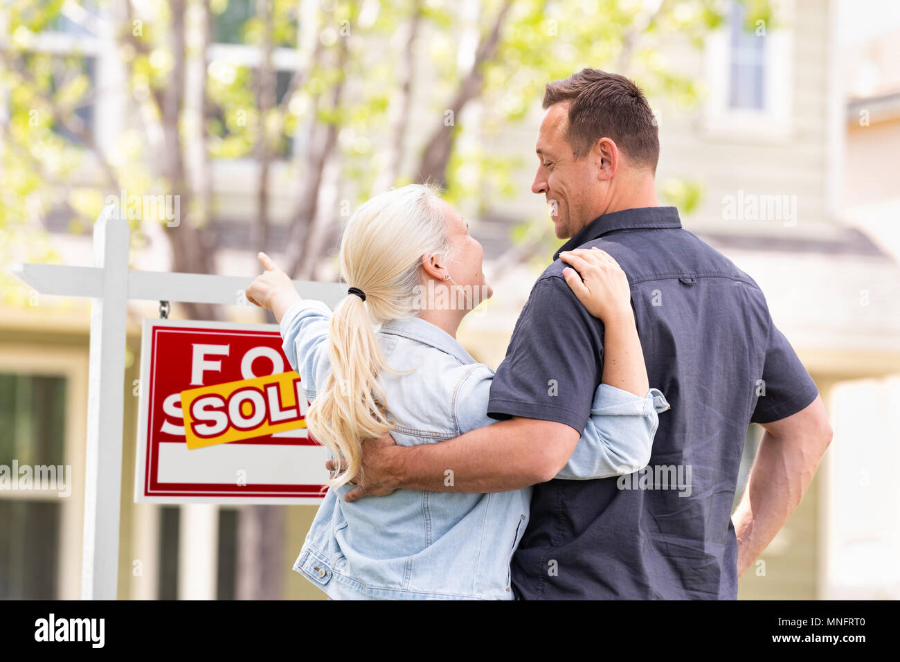 Couple face à face de pointage et vendu enseigne immobilière et de la Chambre. Banque D'Images