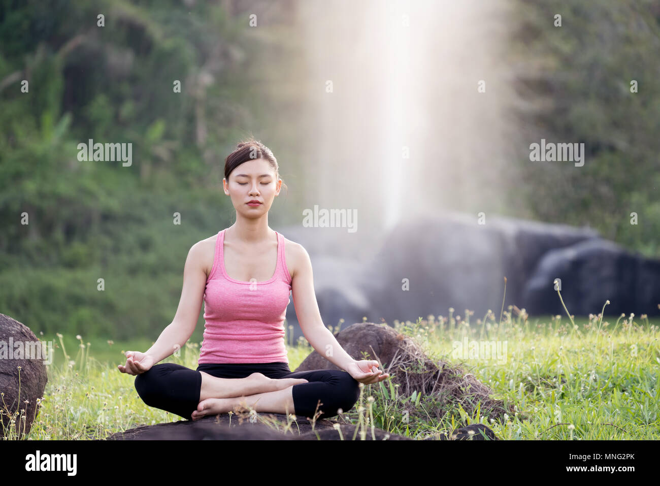 Belle jeune femme asiatique pratiquant le yoga dans le jardin Banque D'Images