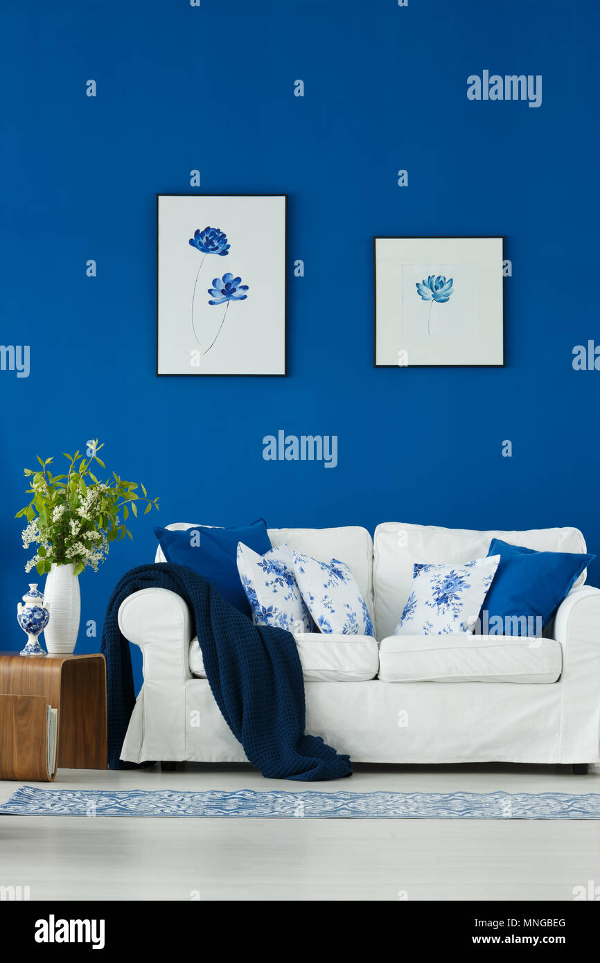 Canapé blanc contre mur bleu avec des affiches Banque D'Images
