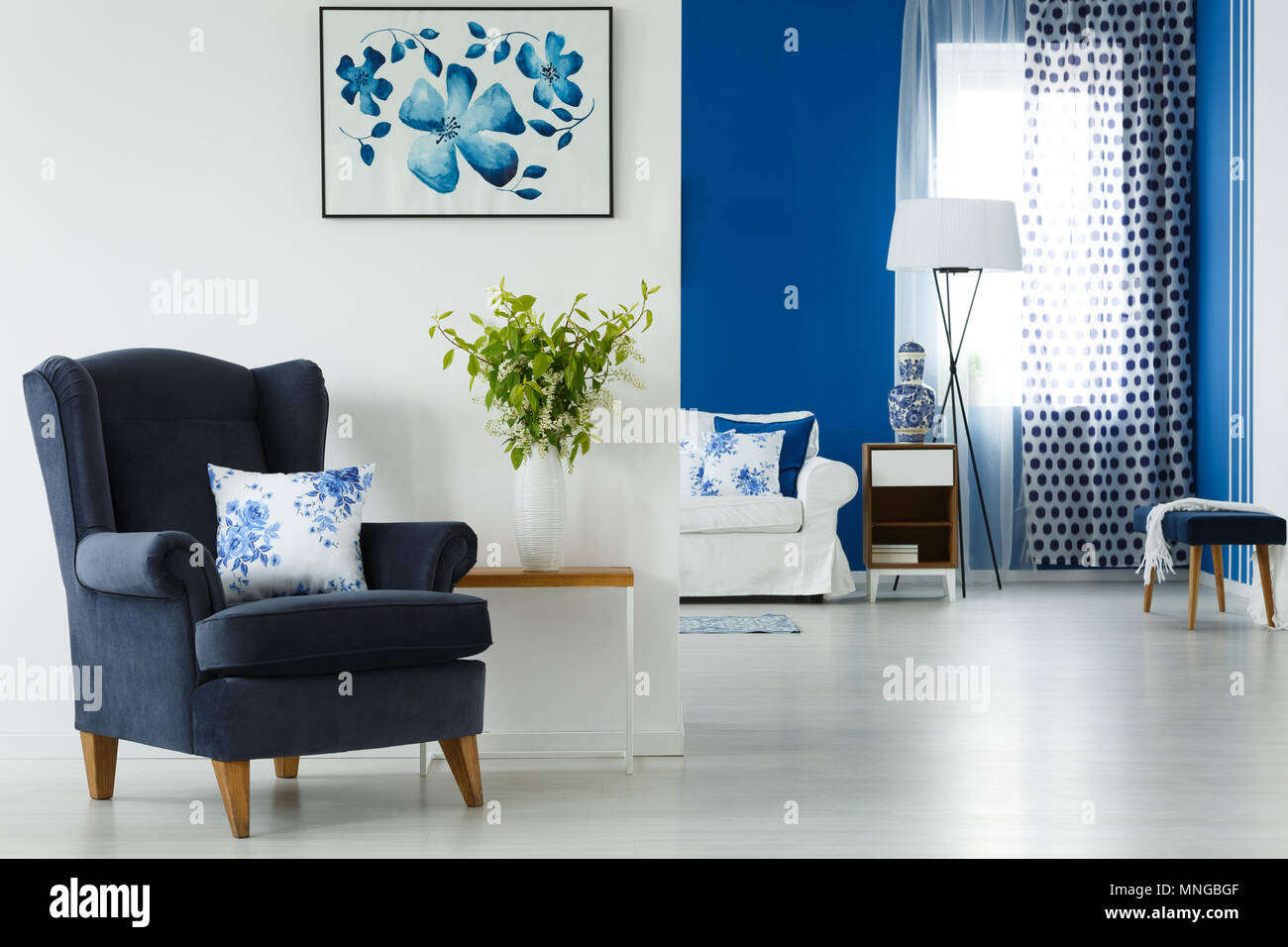 Fauteuil bleu et vase avec fleurs dans un salon élégant Banque D'Images