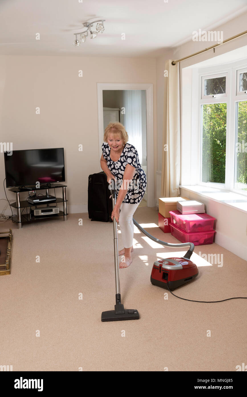 Déménagement, femme à l'aide d'un aspirateur pour aspirateur très hoover le tapis et faire des exercices stretch jambe Banque D'Images