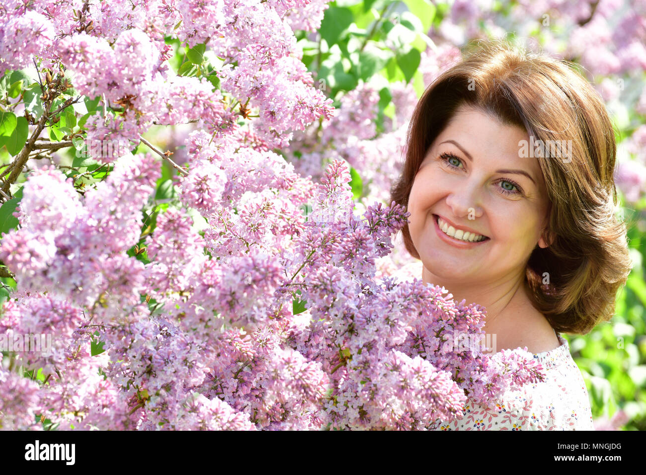 Femme souriante dans alilac jardin au printemps Banque D'Images