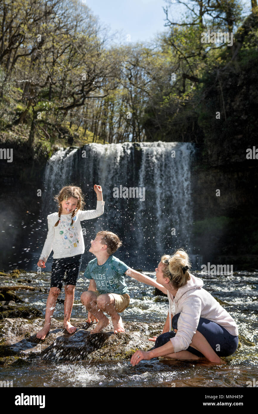 Les quatre cascades à pied près de Pontneddfechan dans les Brecon Beacons - une famille joue dans l'eau à la Sgwd yr Eira falls (chutes de neige) sur la Rive Banque D'Images