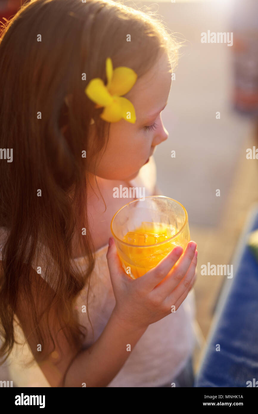 Adorable petite fille boire du jus dans un verre Banque D'Images