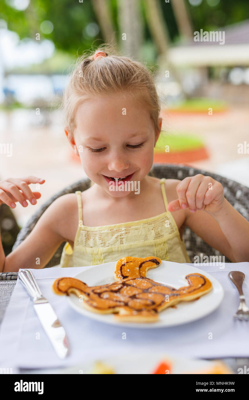 Adorable petite fille manger pour un petit déjeuner aux crêpes au restaurant Banque D'Images