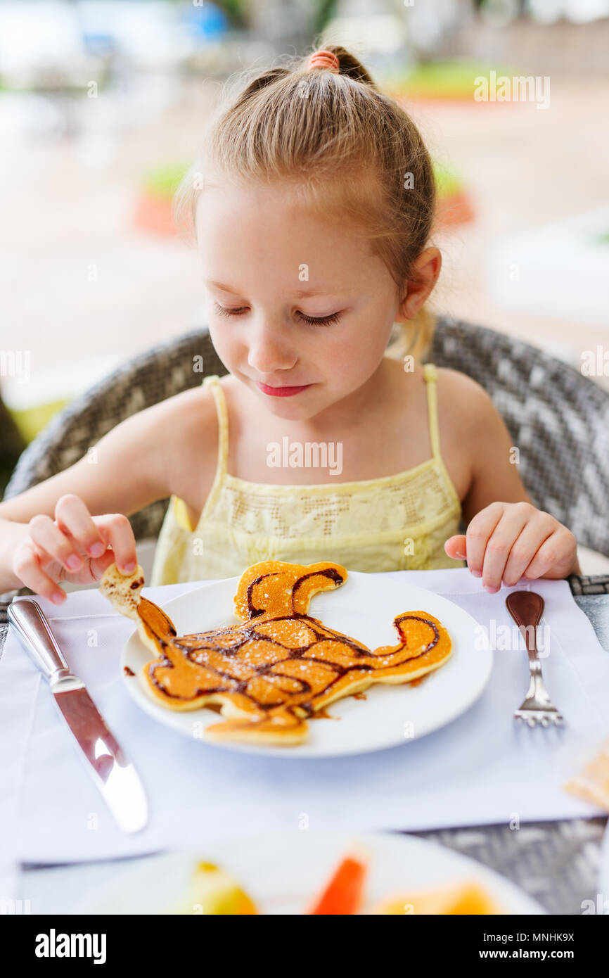 Adorable petite fille manger pour un petit déjeuner aux crêpes au restaurant Banque D'Images