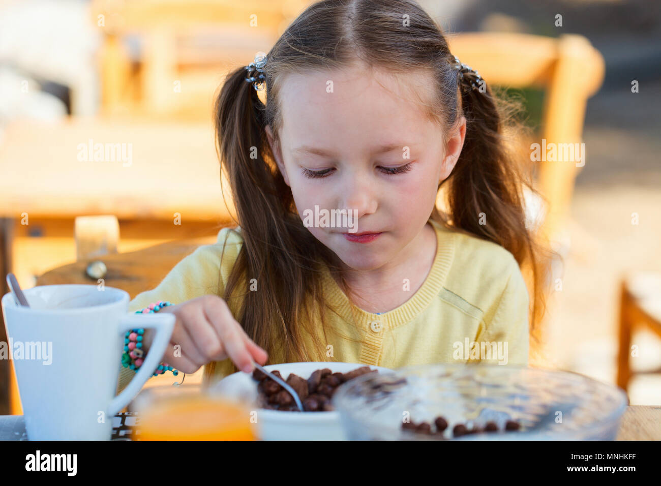 Adorable petite fille manger des céréales avec du lait pour le petit déjeuner Banque D'Images