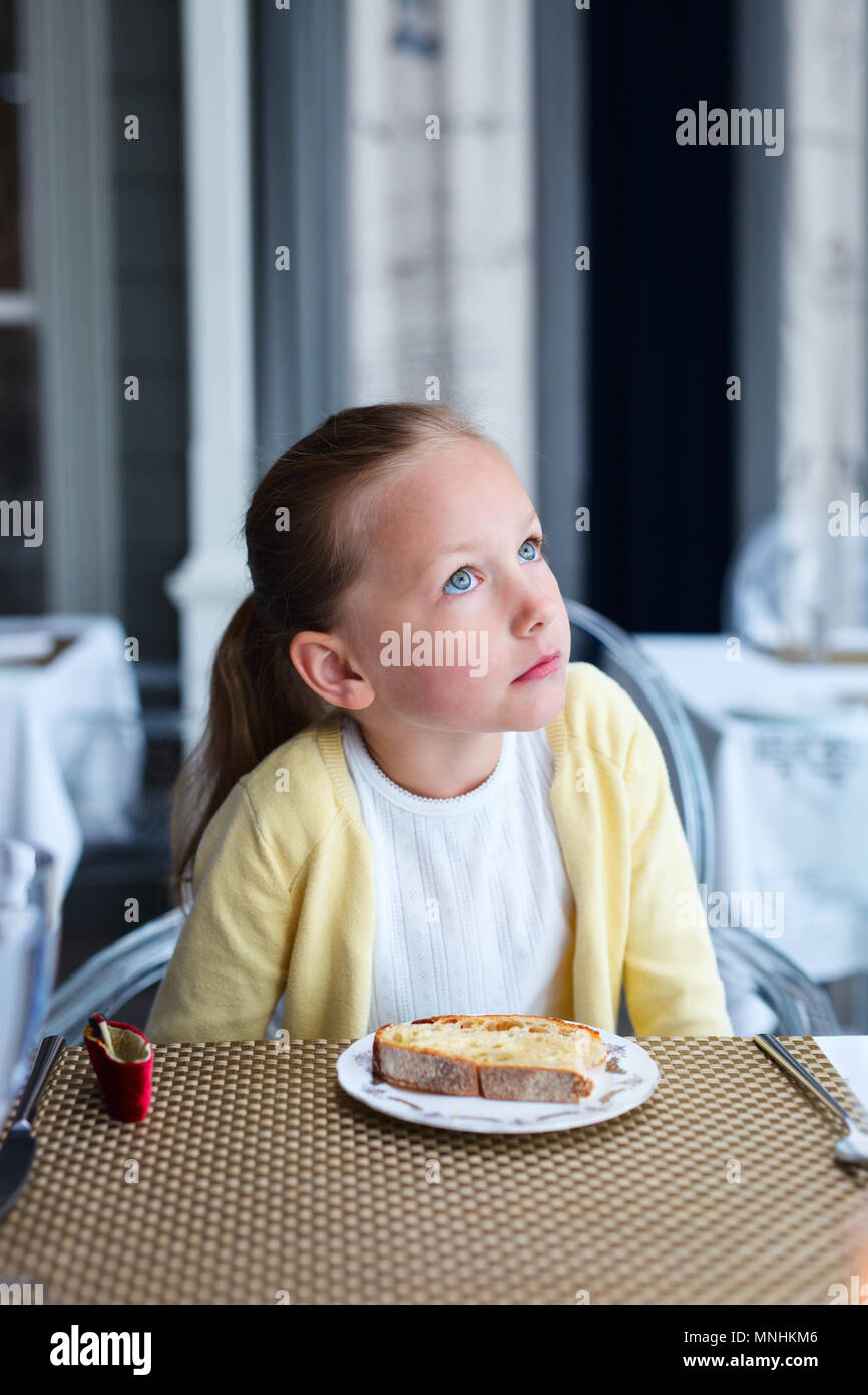 Adorable petite fille au restaurant en attente d'une commande Banque D'Images