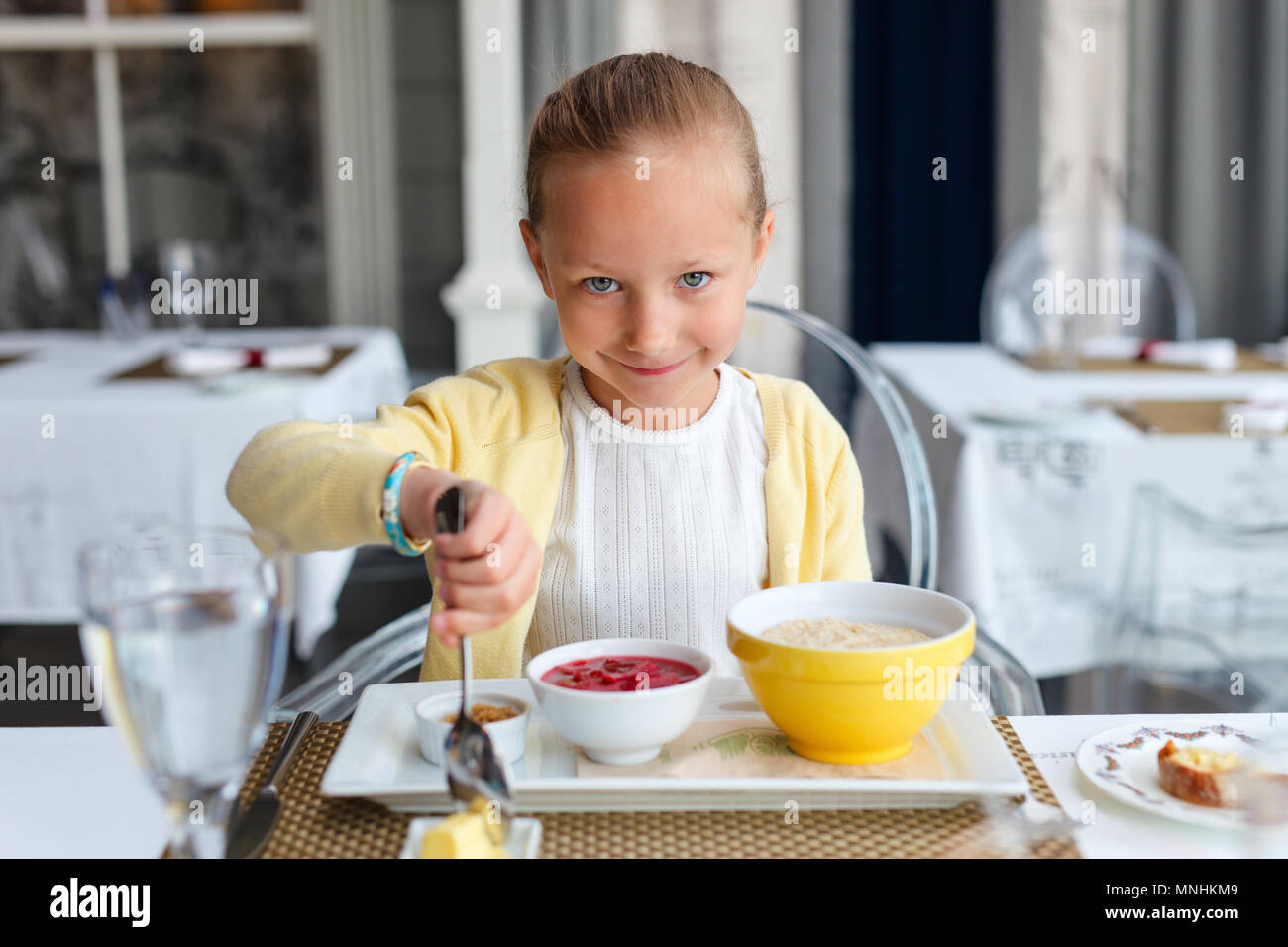 Adorable petite fille manger du gruau pour le petit-déjeuner au restaurant Banque D'Images