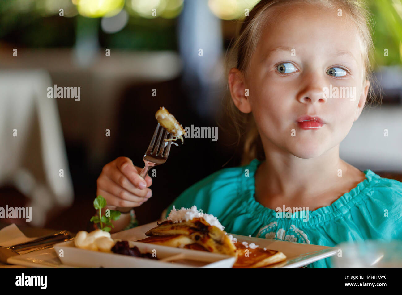 Adorable petite fille qui mange son petit-déjeuner au restaurant Banque D'Images