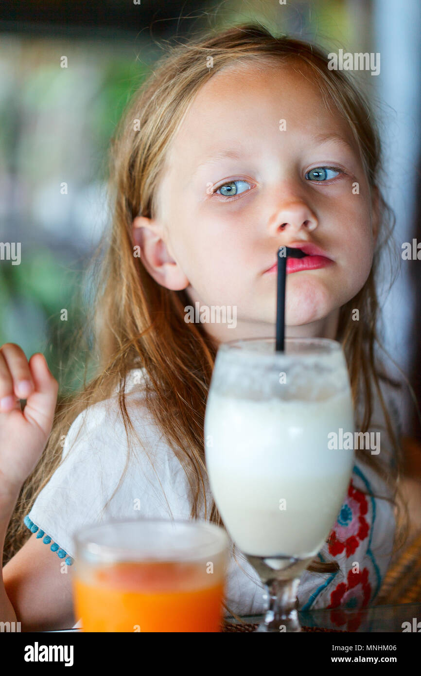 Adorable petite fille boire smoothie frais au café en plein air sur la journée d'été Banque D'Images