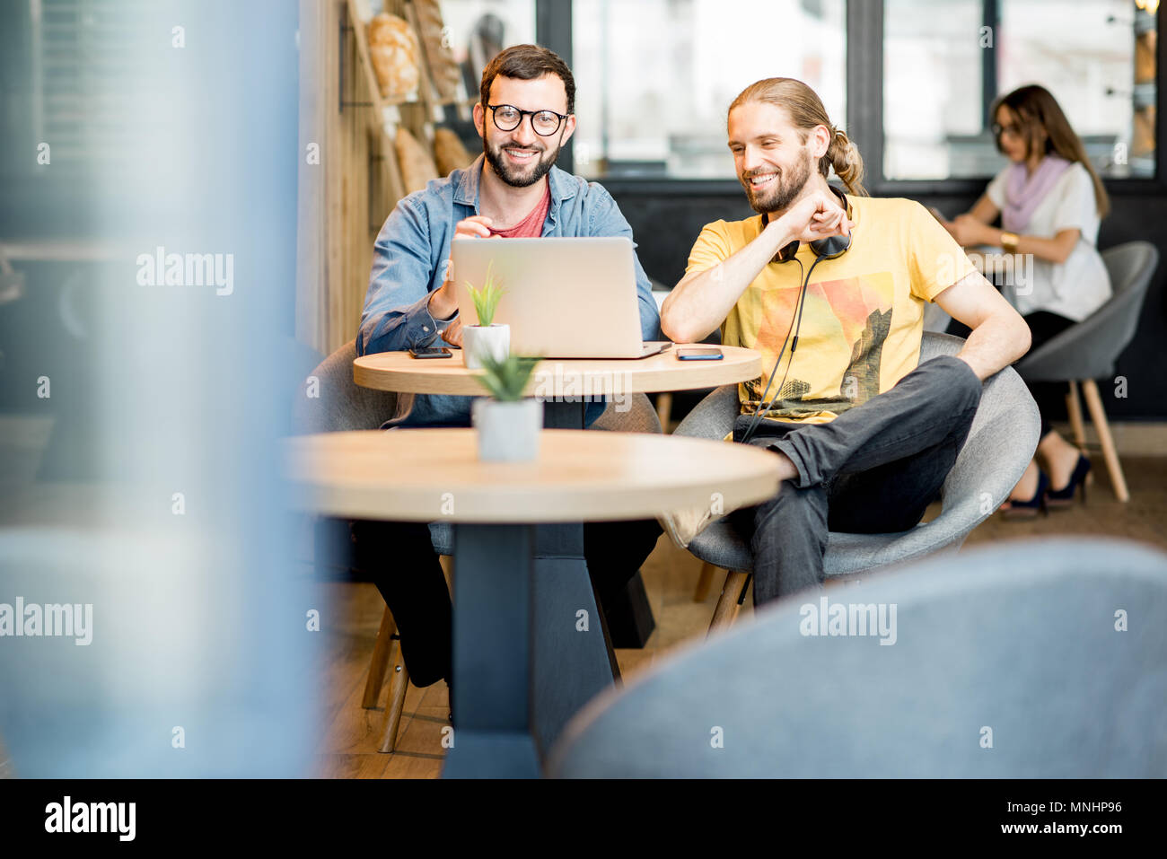 Deux hommes habillés à la légère le travail avec ordinateur portable assis ensemble dans le café Banque D'Images