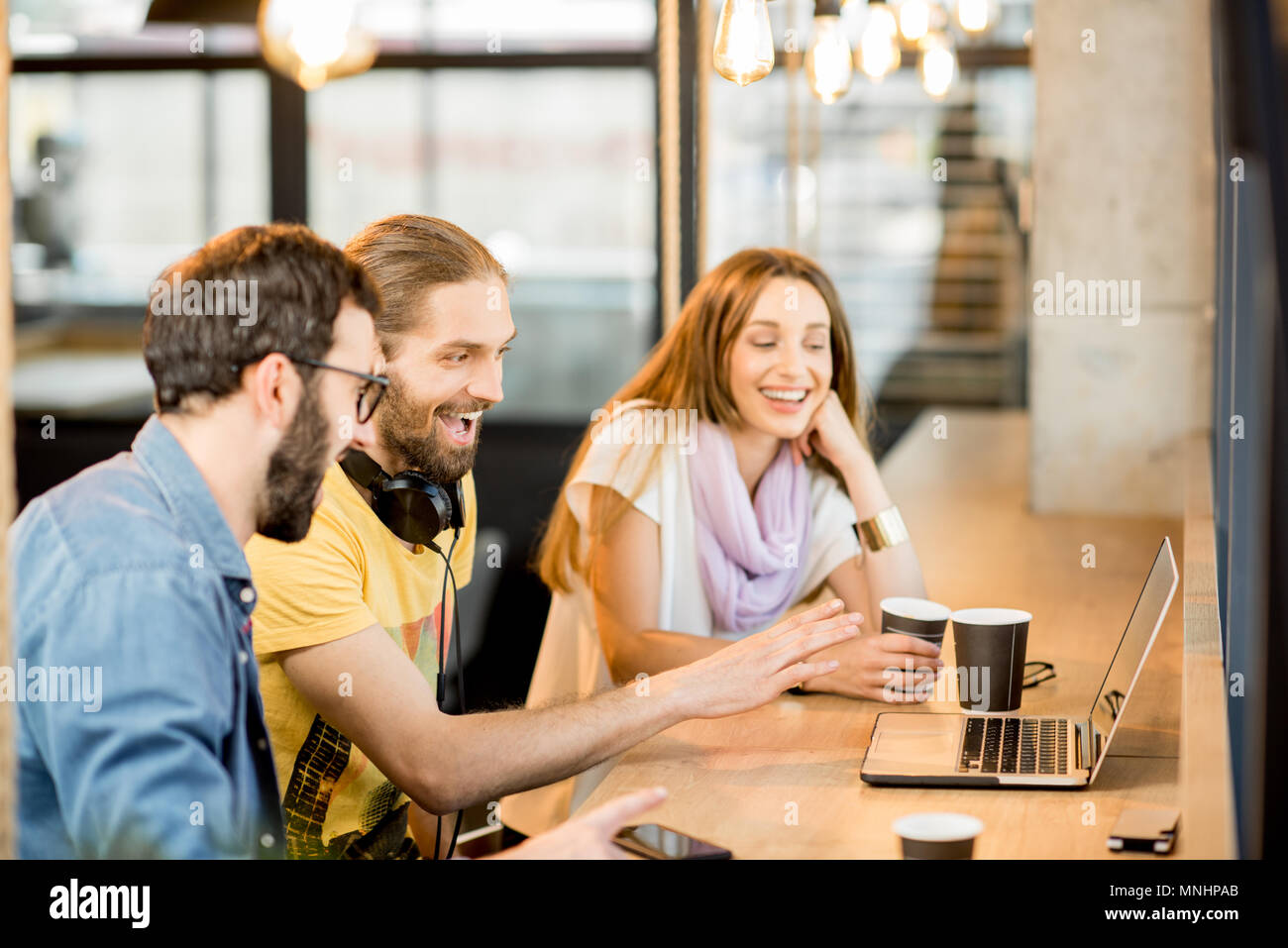 Heureux collègues ayant appel vidéo avec ordinateur portable pendant la pause café au café Banque D'Images