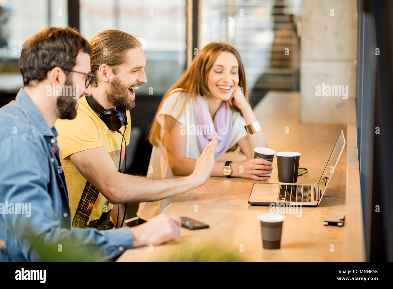 Heureux collègues ayant appel vidéo avec ordinateur portable pendant la pause café au café Banque D'Images