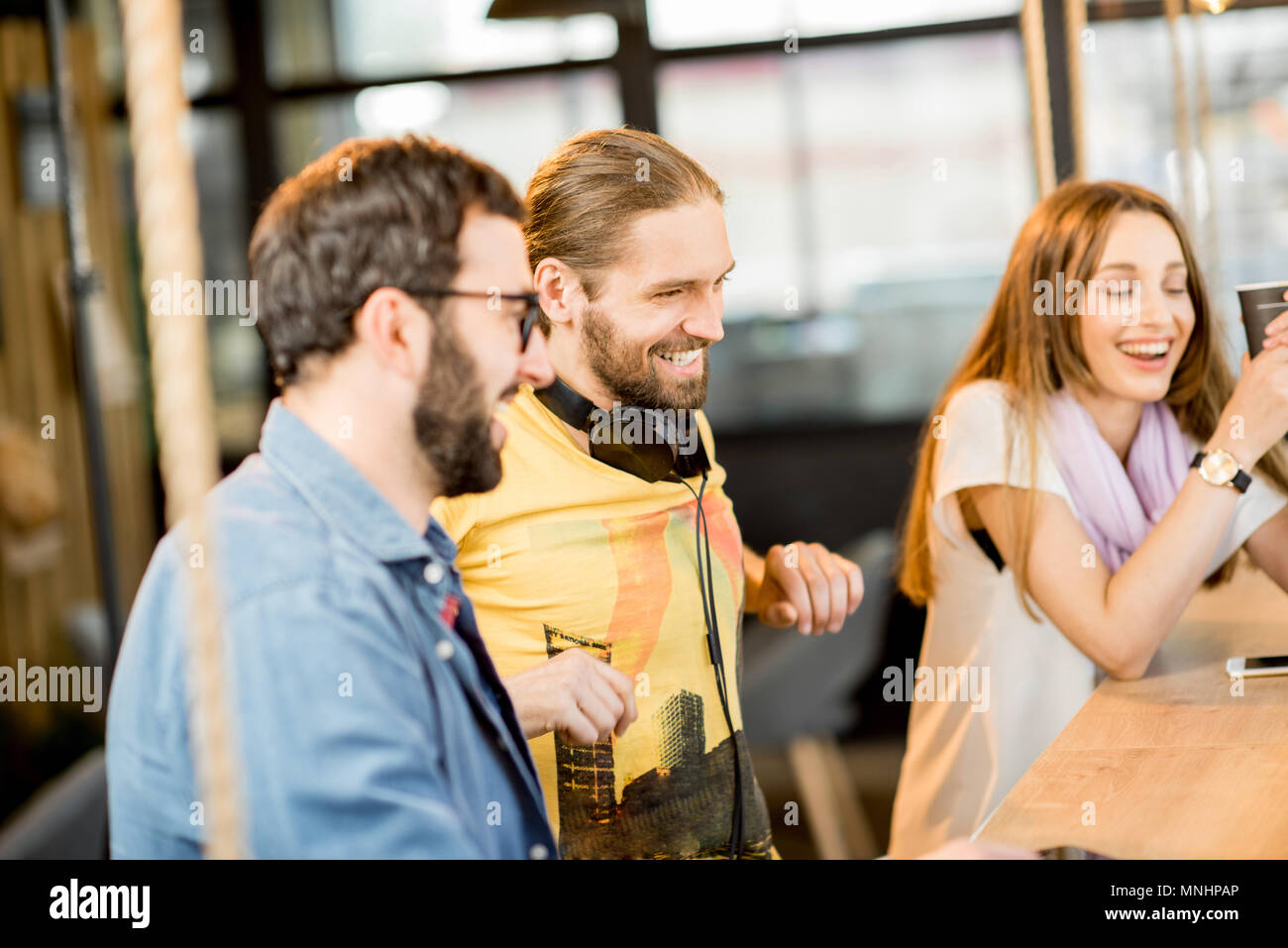 Jeunes collègues habillés de désinvolture assis ensemble pendant la pause café au café Banque D'Images