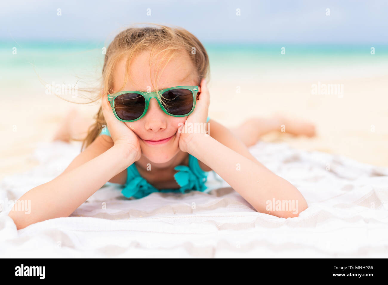 Adorable petite fille allongée sur une serviette de plage pendant ... Adorable petite fille allongée sur une serviette de plage pendant ...