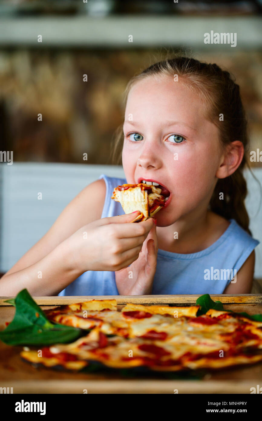 Adorable petite fille manger des pizzas pour le déjeuner Banque D'Images