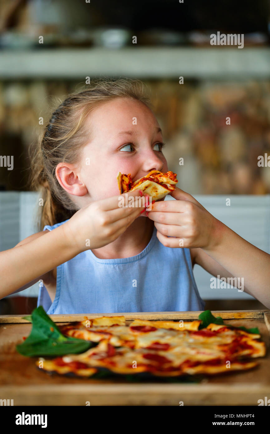 Adorable petite fille manger des pizzas pour le déjeuner Banque D'Images