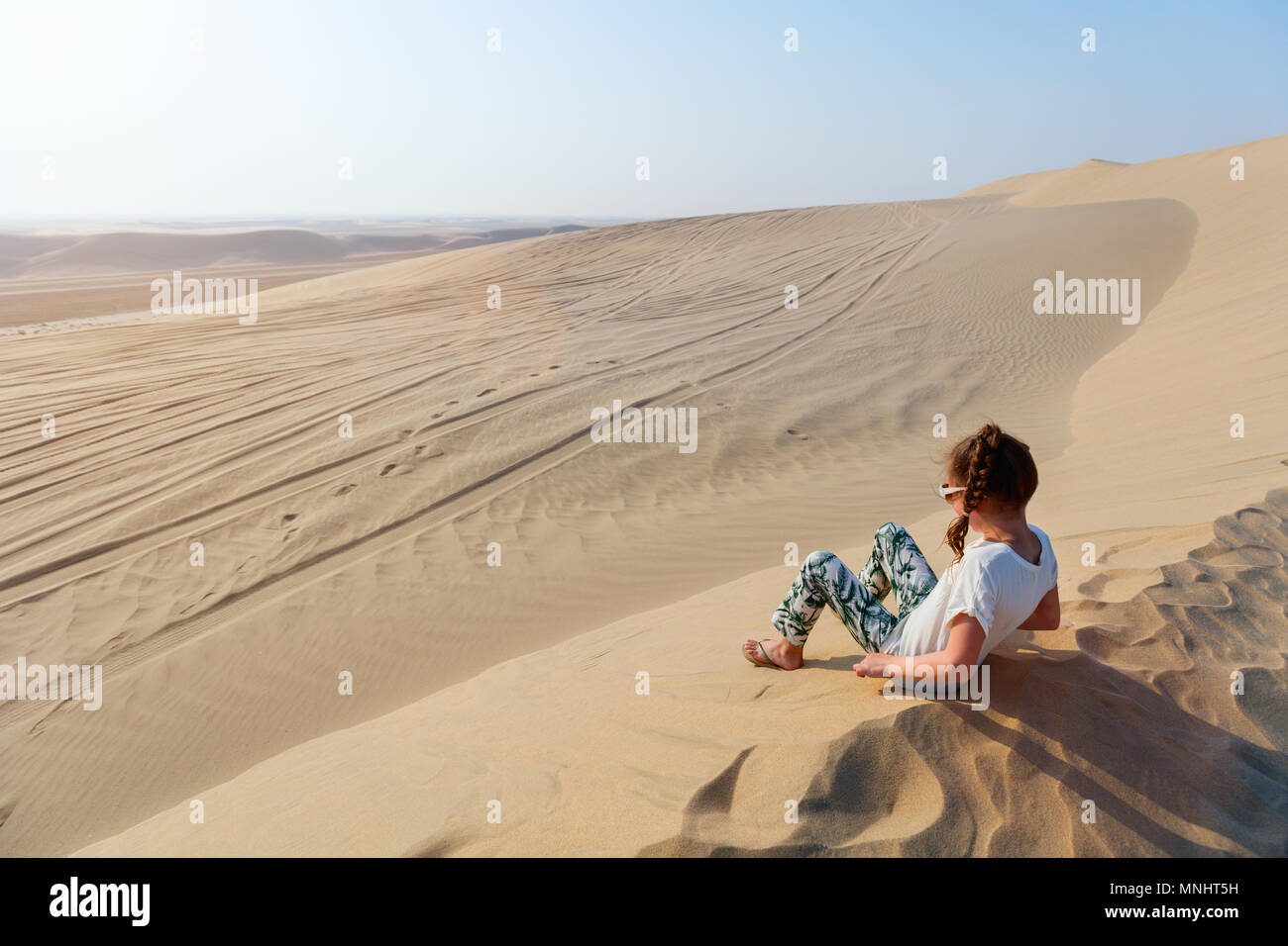 Petite fille s'amusant à jouer sur les dunes de sable du désert au Qatar Banque D'Images