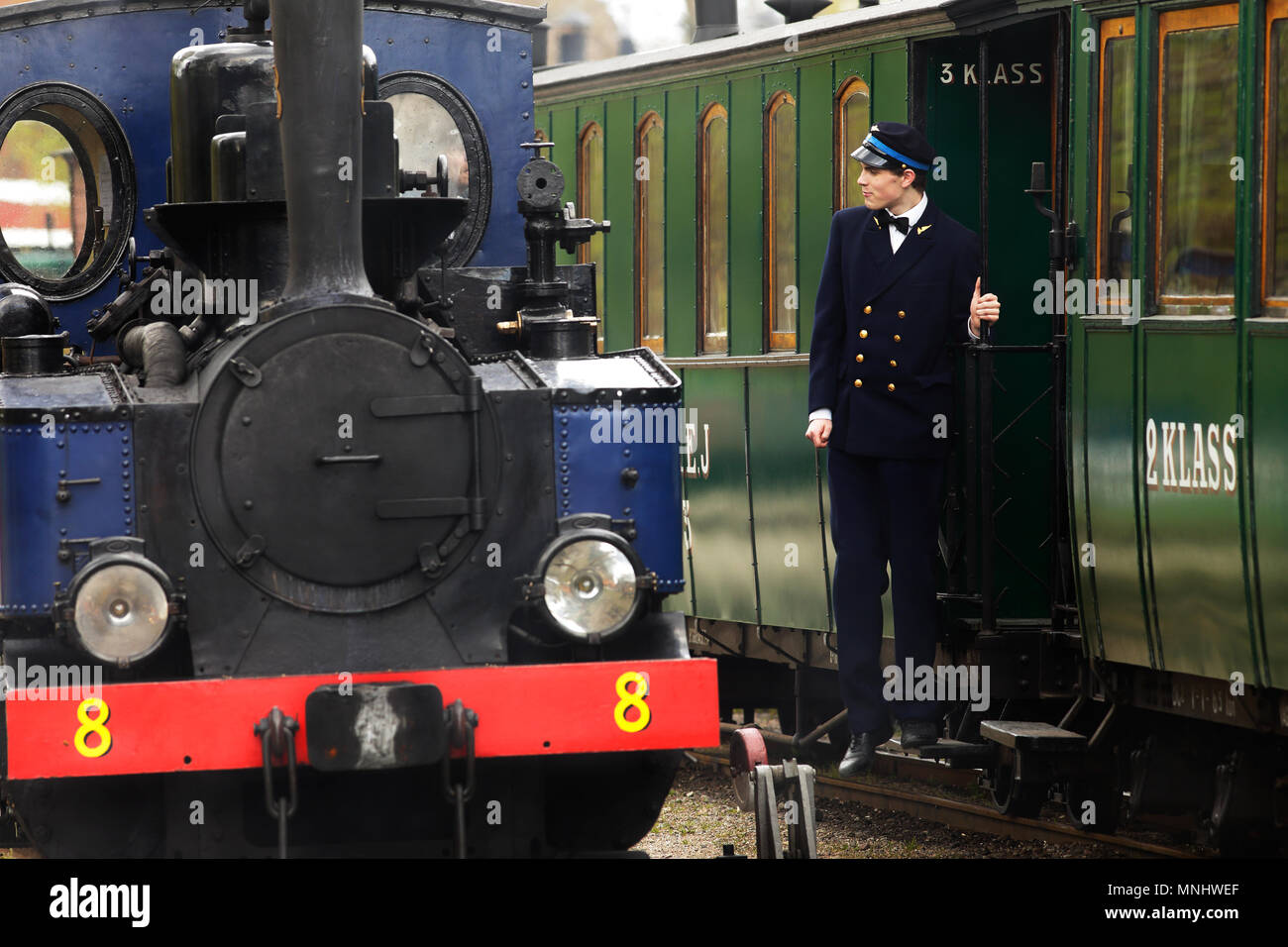 Mariefred, Suède - 11 mai 2013 : le chef de train est sur le marchepied de la voiture à côté de locomotive vapeur numéro 8 Emsfors, au railwa Banque D'Images