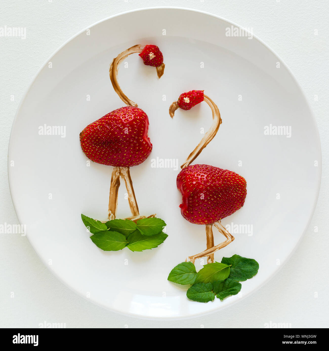Art alimentaire concept créatif. Flamants Roses on white plate. Fraise, Chocolat et menthe composition. Vue d'en haut. Banque D'Images