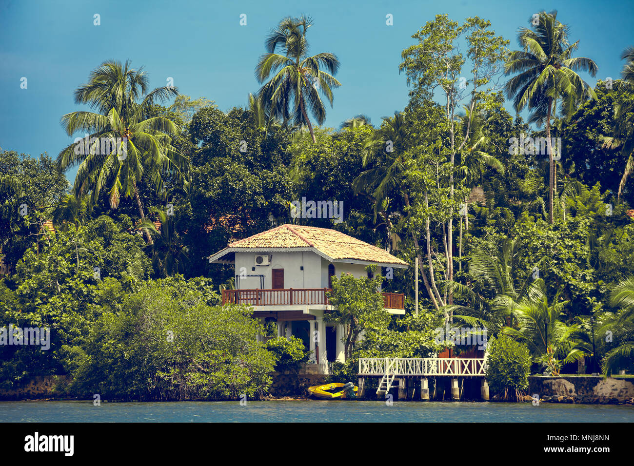 Le bâtiment blanc traditionnel entouré par la forêt tropicale spectaculaire en regard de l'Madu Ganga, l'eau peu profonde du corps. Balapitiya. Au sud-ouest de Sri Banque D'Images