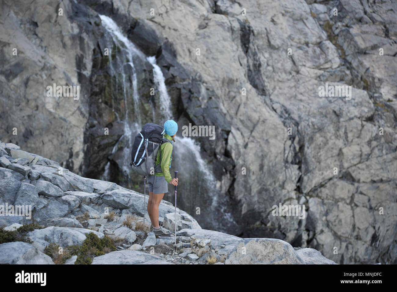 Backpackers hiking passé une cascade de Twin Island Lakes près du Mont Ritter lors d'un trek de deux semaines de la Haute Route dans la Sierra Minarets Wilderness, Inyo National Forest, Californie. La route de 200 milles environ en parallèle avec le John Muir Trail populaire à travers la Sierra Nevada de Californie Plage de Kings Canyon National Park Le Parc National de Yosemite. Banque D'Images