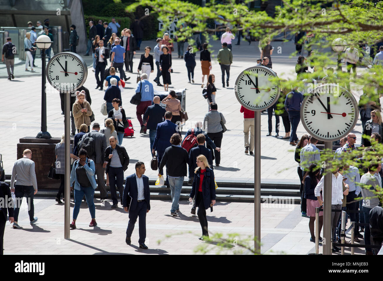 Canary Wharf, horloges indiquent le moment juste avant 12h à l'extérieur de la station de métro avec les employés autour de la mouture le soleil brille, Banque D'Images