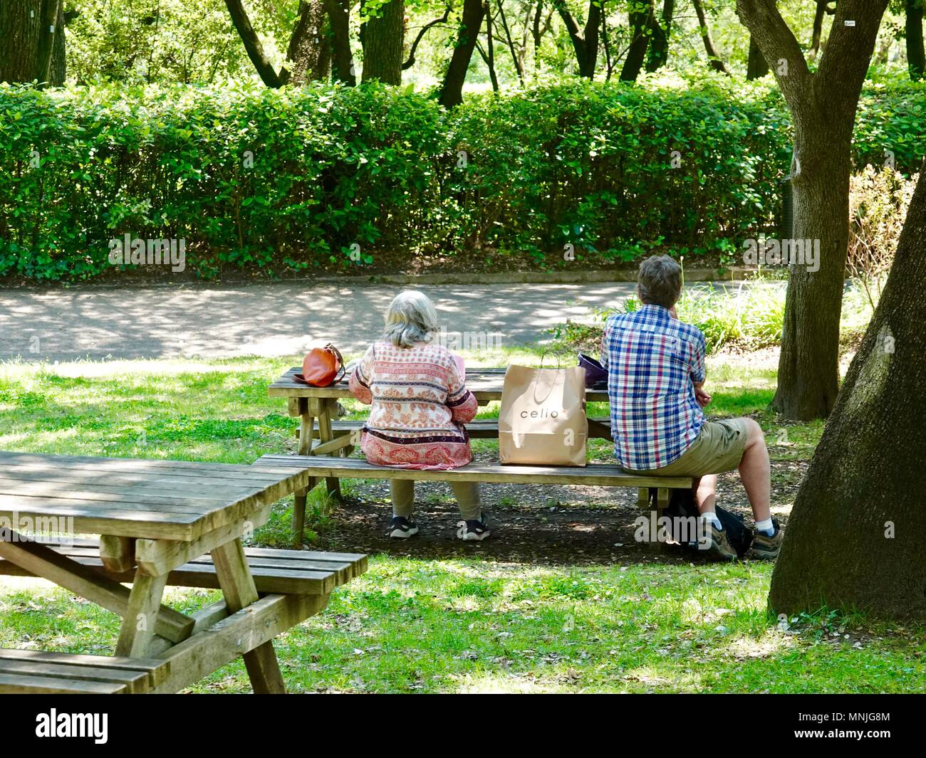 Couple d'âge moyen de manger le déjeuner de pique-nique à table dans la Jardins de la fontaine, Nîmes, France Banque D'Images