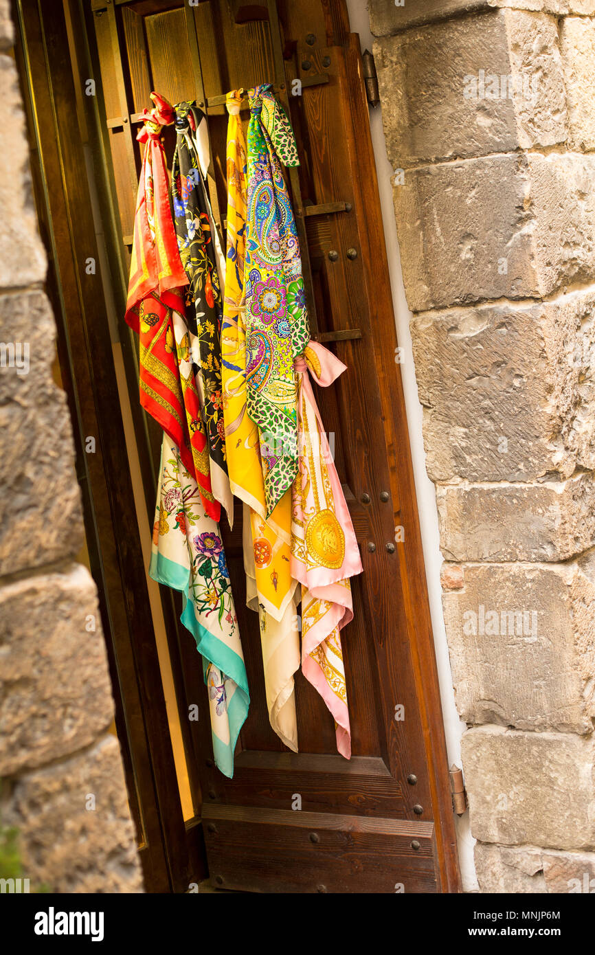Foulards colorés exposés à la vente sur une porte en bois traditionnels d'un édifice de pierre dans le centre-ville de Florence, Florence, Toscane, Italie Banque D'Images