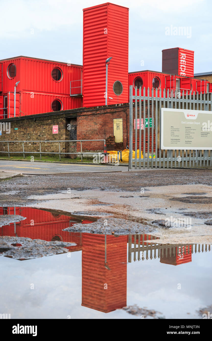 Réflexions dans l'eau de pluie de l'East London Veolia rouge Depot, peuplier, London, UK Banque D'Images