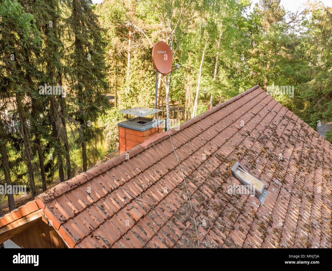 Survol de la toiture d'une maison individuelle à vérifier l'état de l'antenne satellite pour la réception de télévision et Internet, vue aérienne, m Banque D'Images