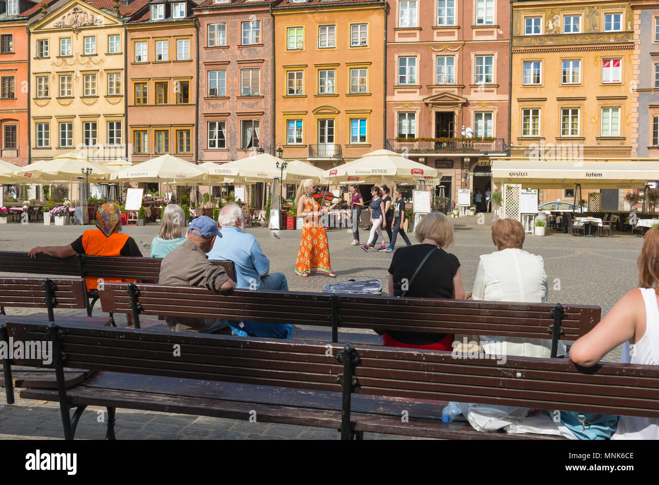 La vieille ville de Varsovie, un violoniste reçoit un groupe de personnes assises sur des bancs dans l'historique place de la vieille ville de Varsovie, Pologne. Banque D'Images