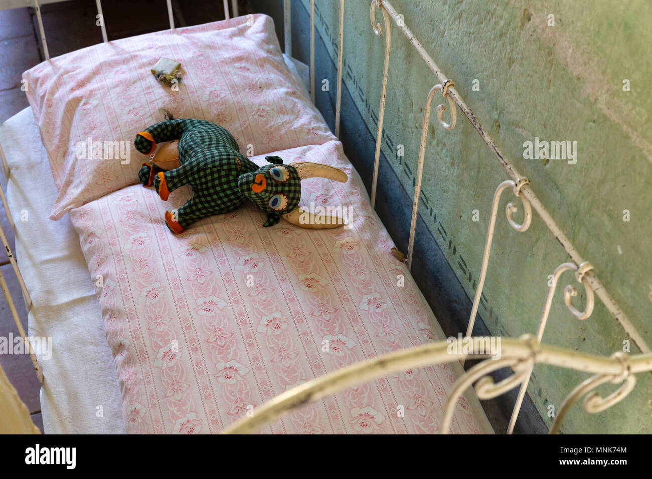Concept d'une enfance pauvre et triste. Vieux usé handmade stuffed animal  couché sur un petit lit de fortune dans une chambre sombre Photo Stock -  Alamy