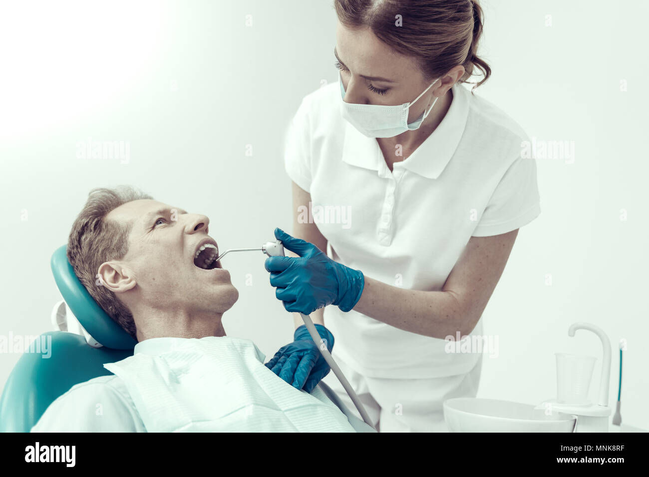 Dentiste graves guérir son patient avec une aide d'un moteur dentaire Banque D'Images