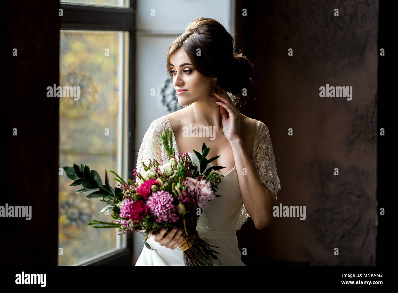 Belle robe de mariée assis sur une chaise à l'intérieur dans dark studio intérieur comme à la maison. Banque D'Images