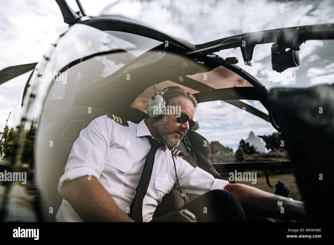 L'exploitation pilote masculin de commutateurs système d'hélicoptère avant le départ. Assis à l'intérieur du poste de pilotage pilote d'hélicoptère. Banque D'Images