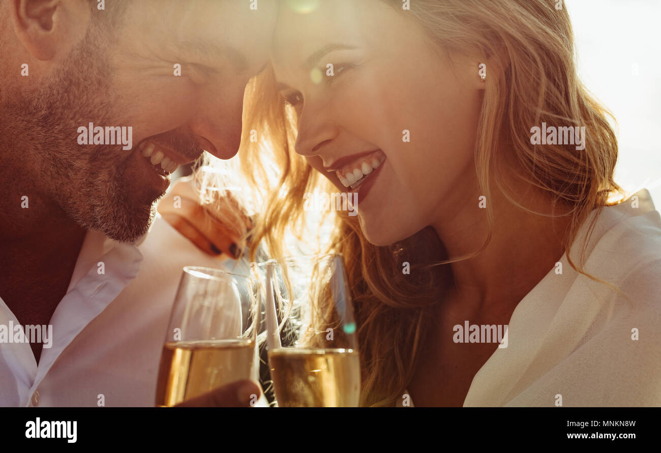 Portrait d'un couple romantique avec leurs têtes ensemble tenant un verre de vin. Couple avec wine smiling outdoors. Banque D'Images