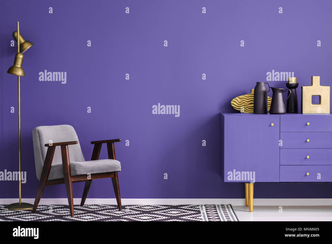 Vases noir sur violet près du cabinet fauteuil gris et la lampe dans le salon intérieur avec des tapis à motifs Banque D'Images