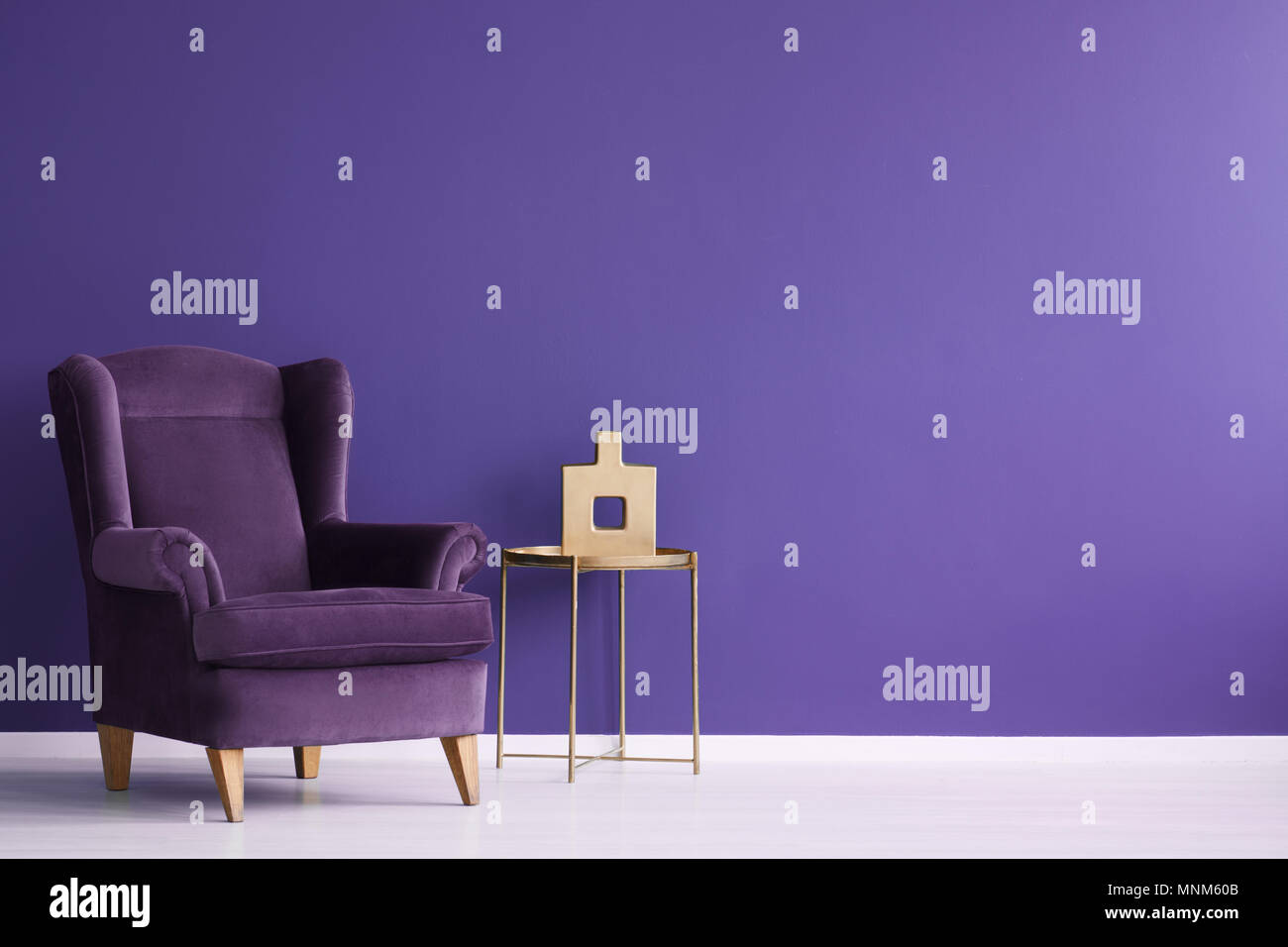 Vase sur la table d'or à côté d'un fauteuil en velours pourpre violet minimal intérieur salon with copy space Banque D'Images