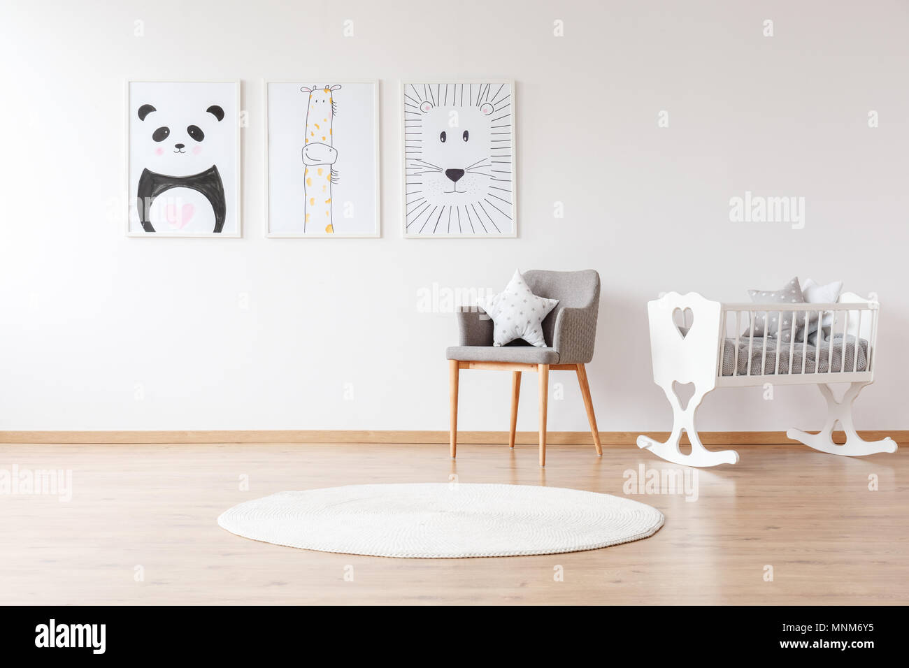 Chaise gris et blanc avec oreiller tapis rond près de white lit bébé dans la chambre de bébé avec animal posters sur le mur Banque D'Images